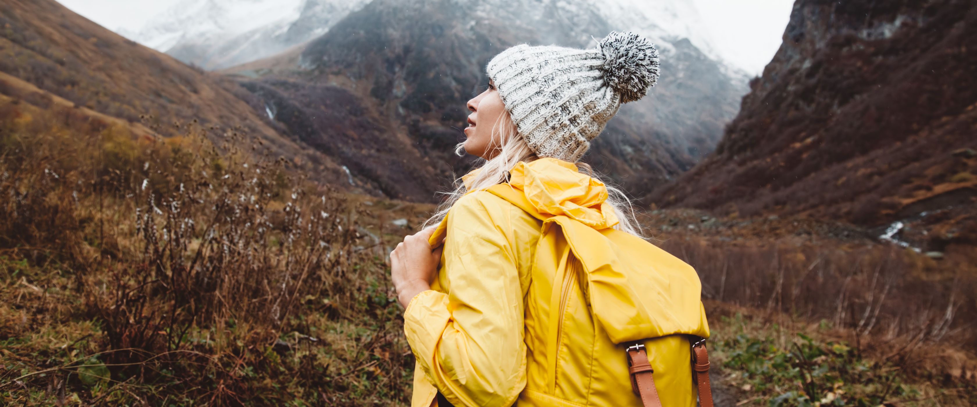 Woman in yellow raincoat with mountain 