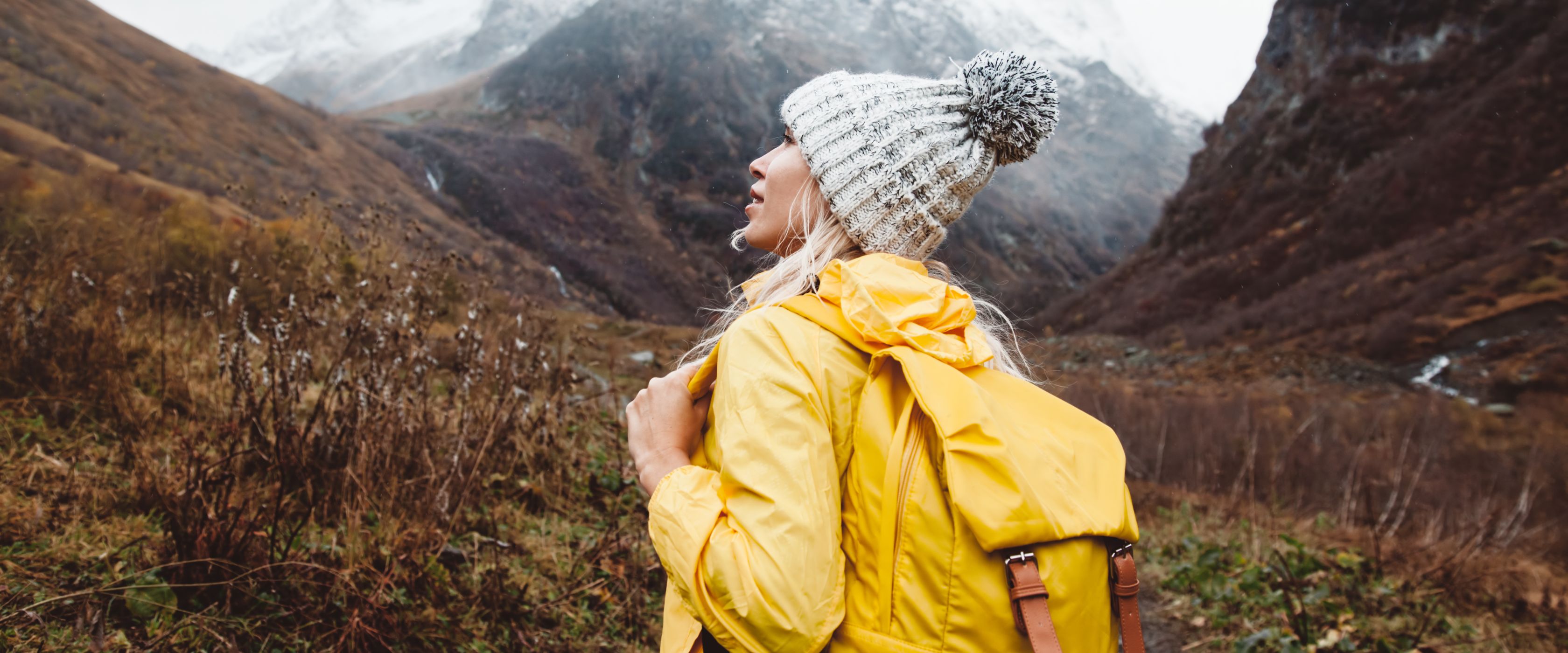 Woman in yellow raincoat with mountain