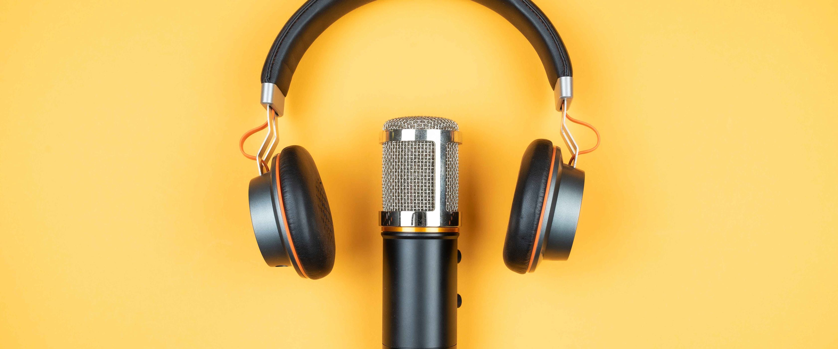 Podcast microphone and headphones on yellow background