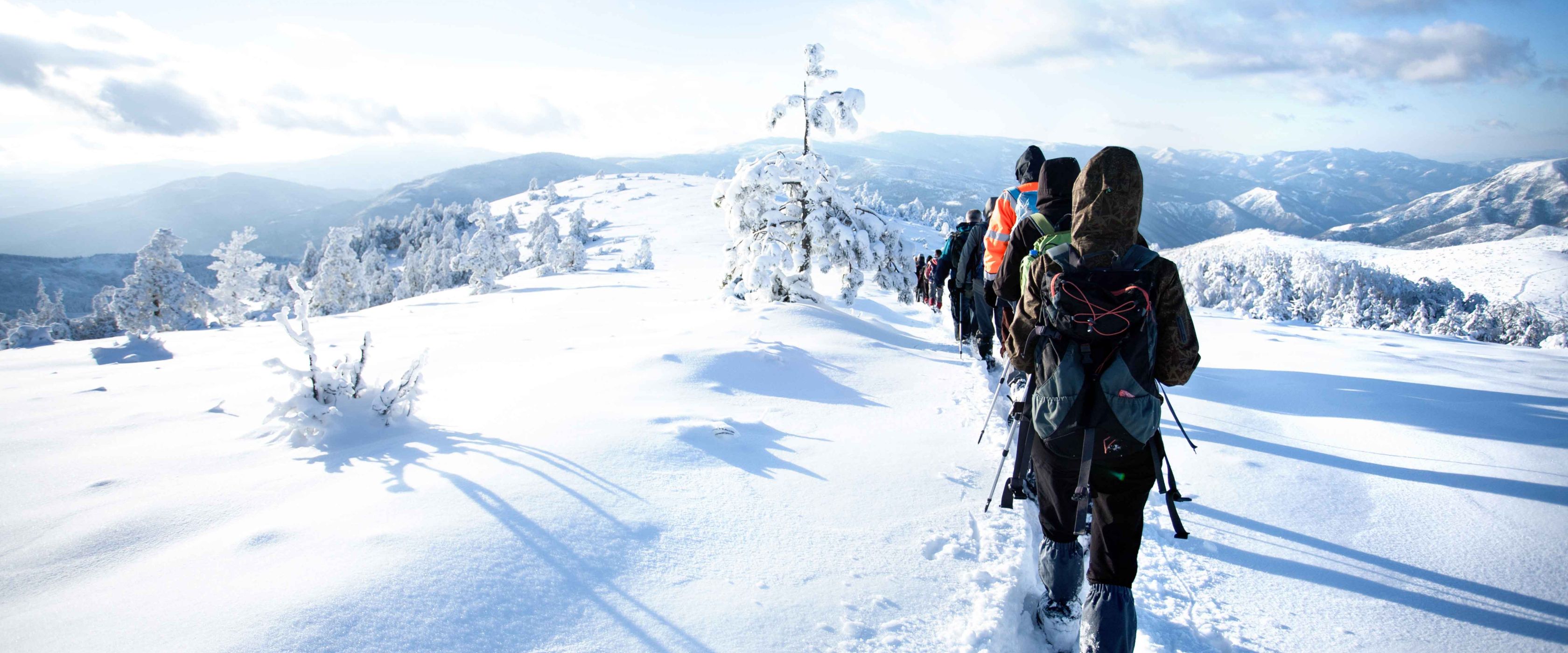 People show shoeing through snowy hills