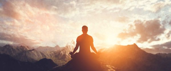 Man meditating on cliff ledge