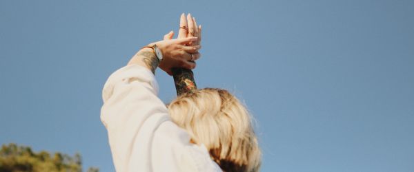 women reaching hands up into the sky