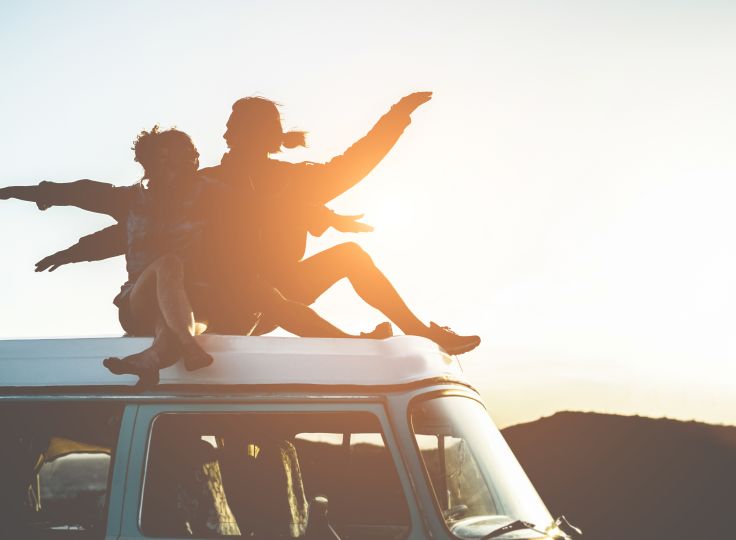 Two people sitting on a Van in the sunset