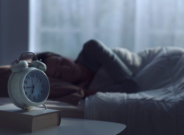 Woman sleeping with alarm clock next to her