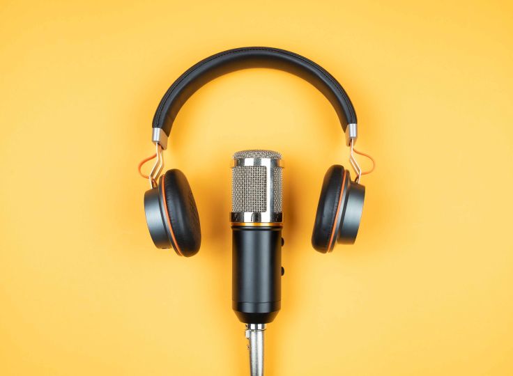 Podcast microphone and headphones on yellow background
