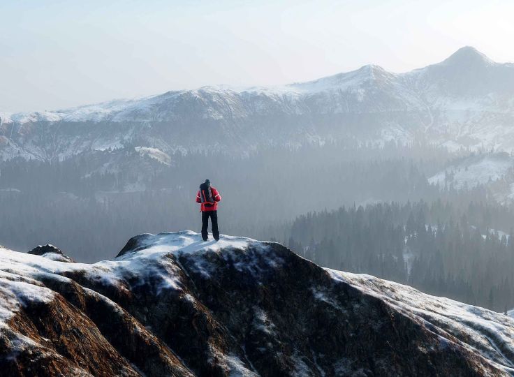 Man standing on top snow capped mountain