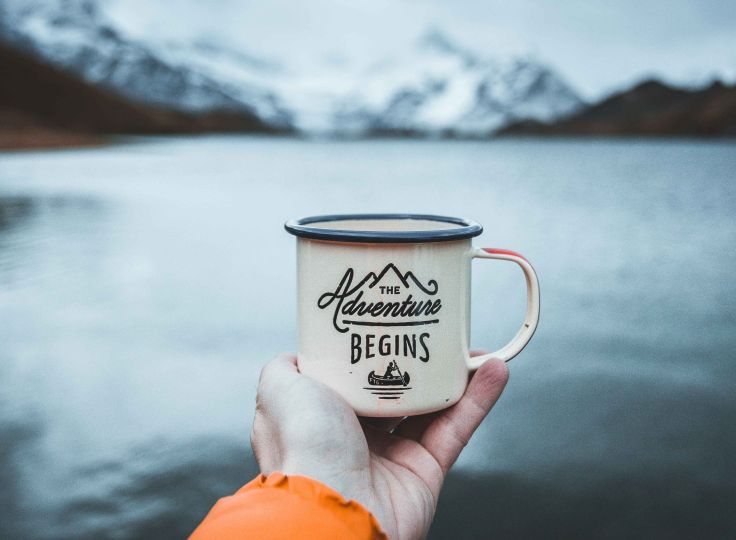 Someone holding mug in front of a lake