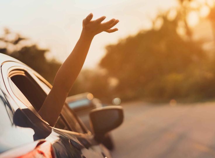 Person driving with hand out the window