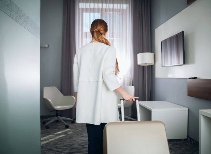 Therapist enters short-term furnished apartment with suitcase