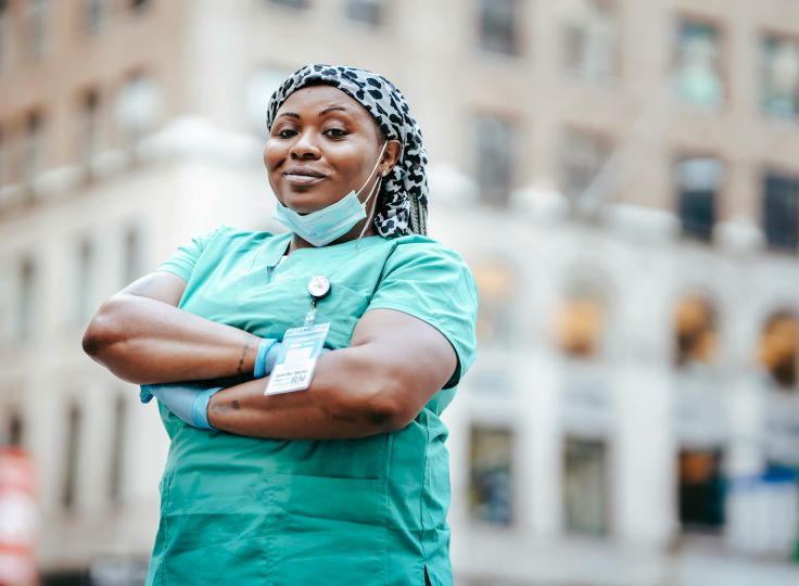 Black nurse standing proudly in scrubs and badge