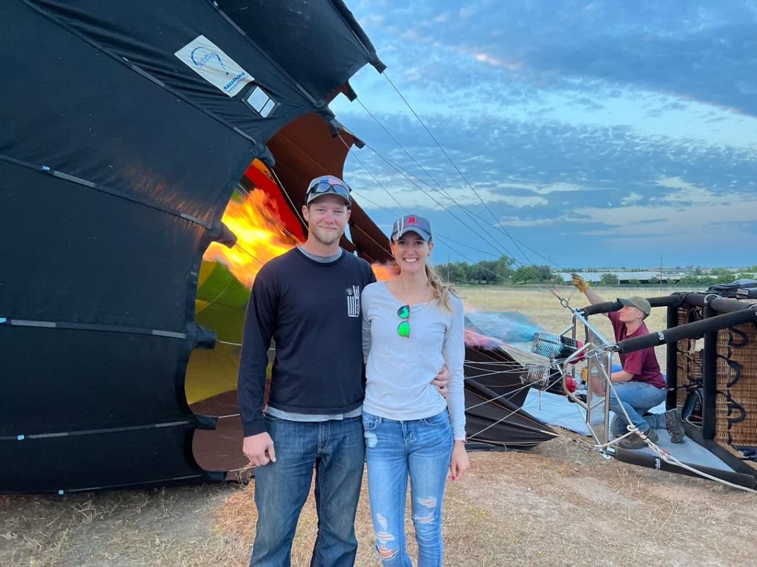 Woman and man standing in front of grounded hot air balloon