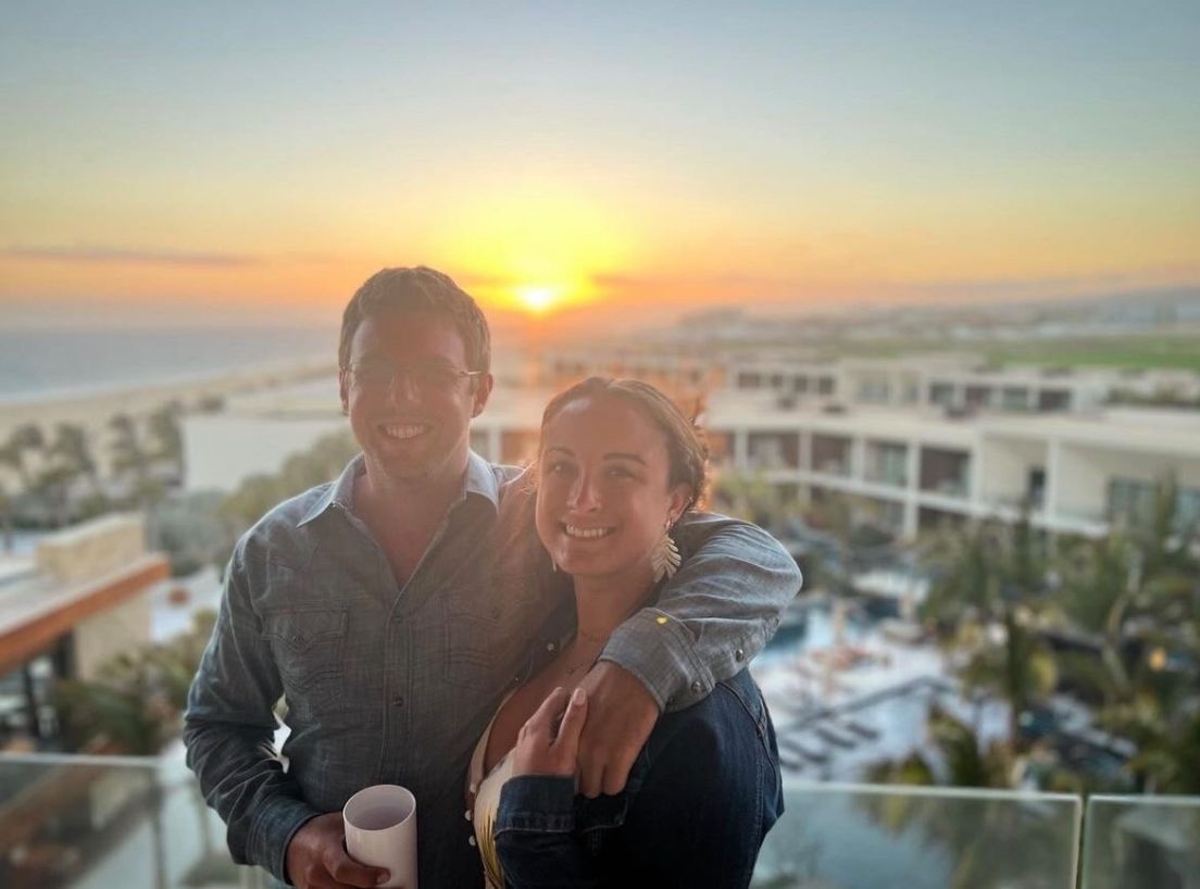 Man and woman smiling with sunset behind them