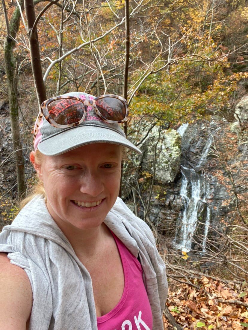 Woman hiking with waterfall behind her