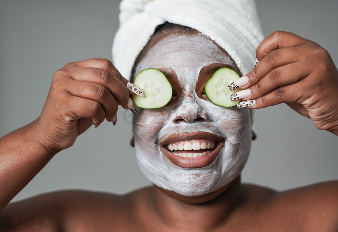 Woman with face mask and cucumbers on her eyes