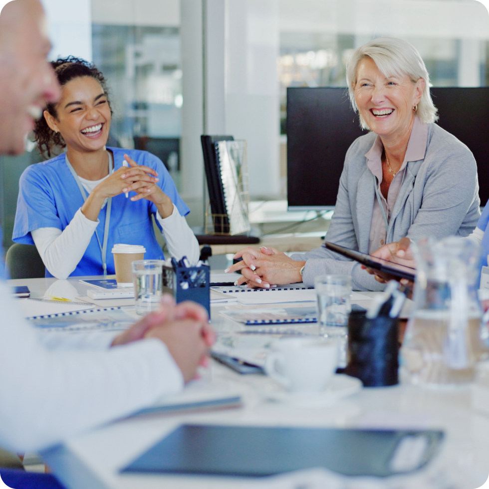 A team of health care professionals laugh around a conference table