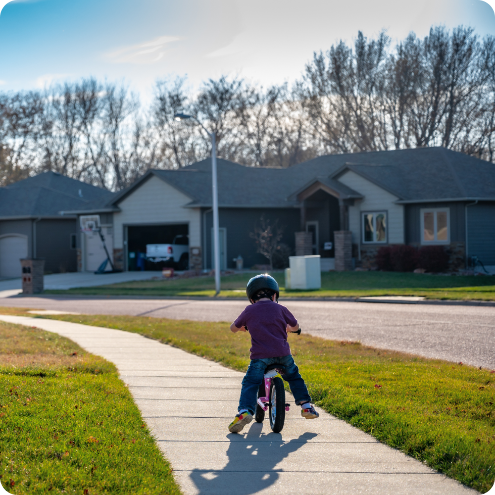 A young child rides a bicycle on the sidewalk