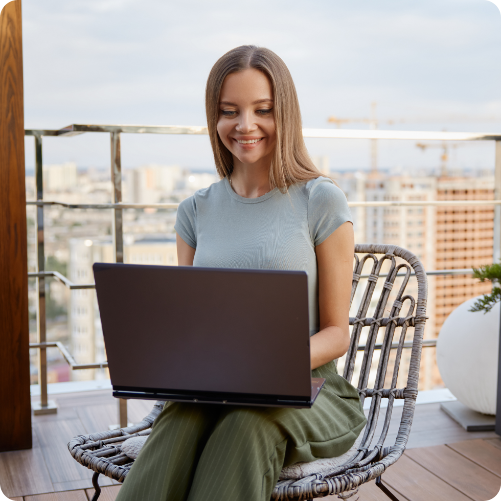 A clinician enjoys the balcony of their travel housing while working on their laptop