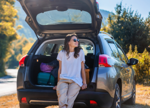 A clinician rests on the bumper of her car while before taking a hike during her time off 