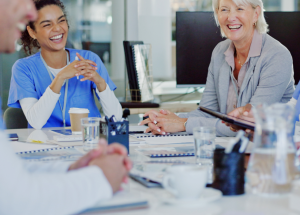 A team of health care professionals laugh around a conference table