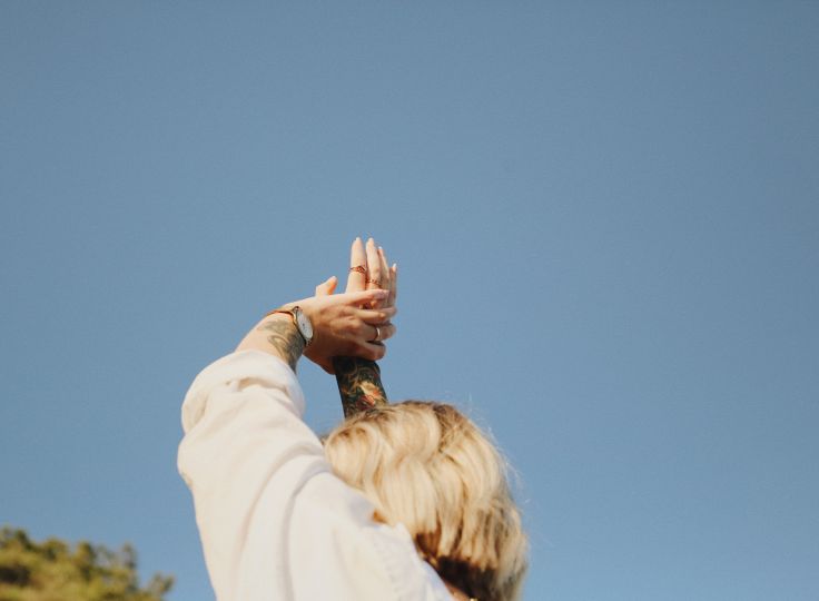 women reaching hands up into the sky