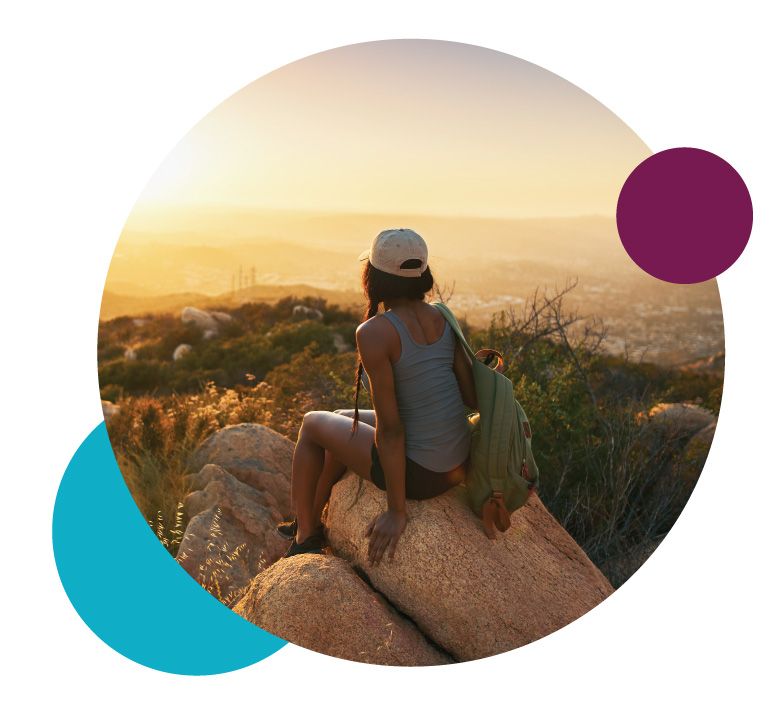 Woman sitting on rock looking at sunset